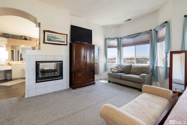 living room featuring a tile fireplace and carpet flooring