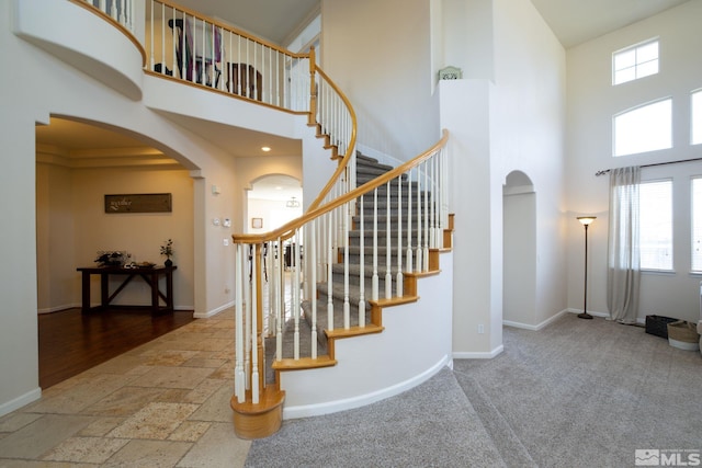 stairs featuring a healthy amount of sunlight, a towering ceiling, and carpet floors