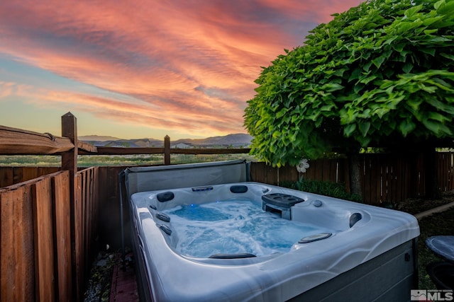 patio terrace at dusk with a mountain view and a hot tub