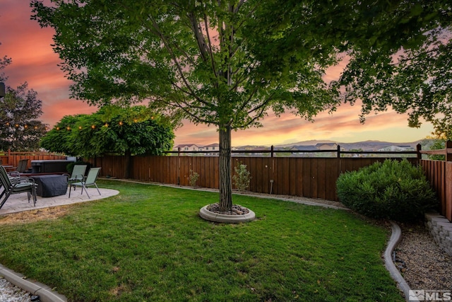 yard at dusk featuring a patio area and a mountain view