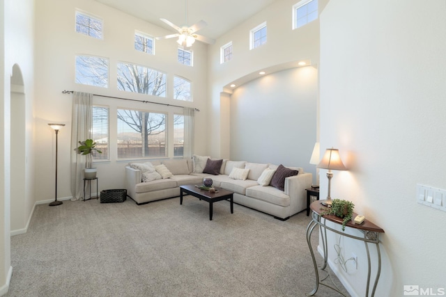 living room featuring a high ceiling, light colored carpet, and ceiling fan