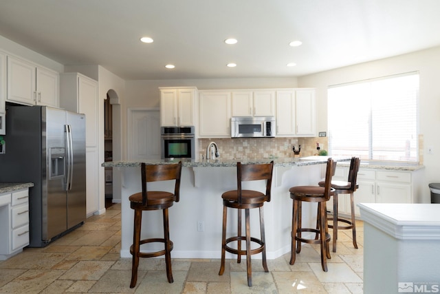 kitchen with white cabinets, appliances with stainless steel finishes, a center island, and backsplash