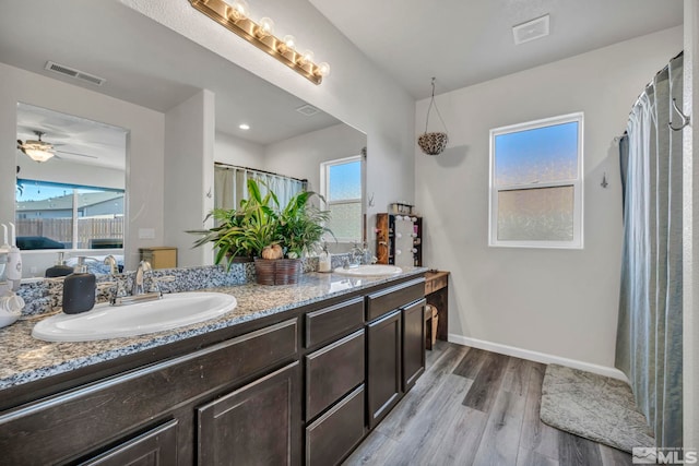 bathroom with a wealth of natural light, vanity, wood-type flooring, and ceiling fan