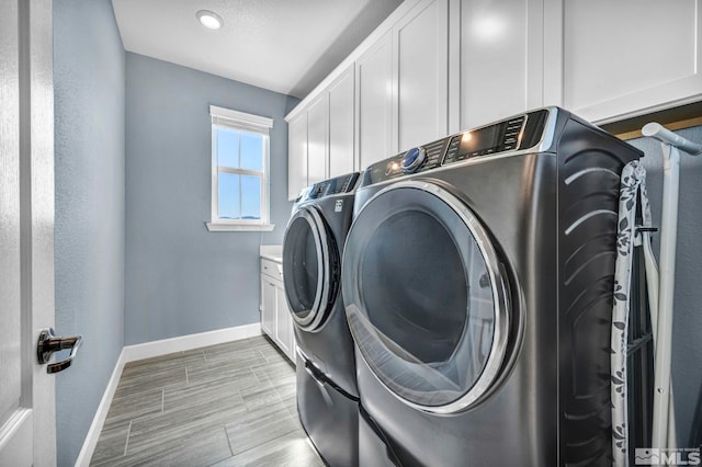 washroom with washer and clothes dryer, cabinets, and light wood-type flooring