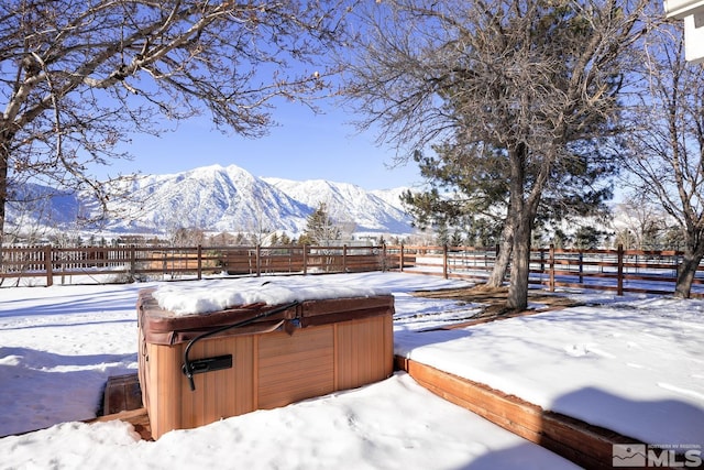 yard covered in snow with a mountain view, a rural view, and a hot tub