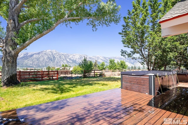 deck featuring a lawn, a mountain view, and a hot tub