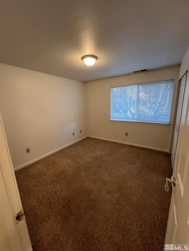 unfurnished room featuring dark carpet