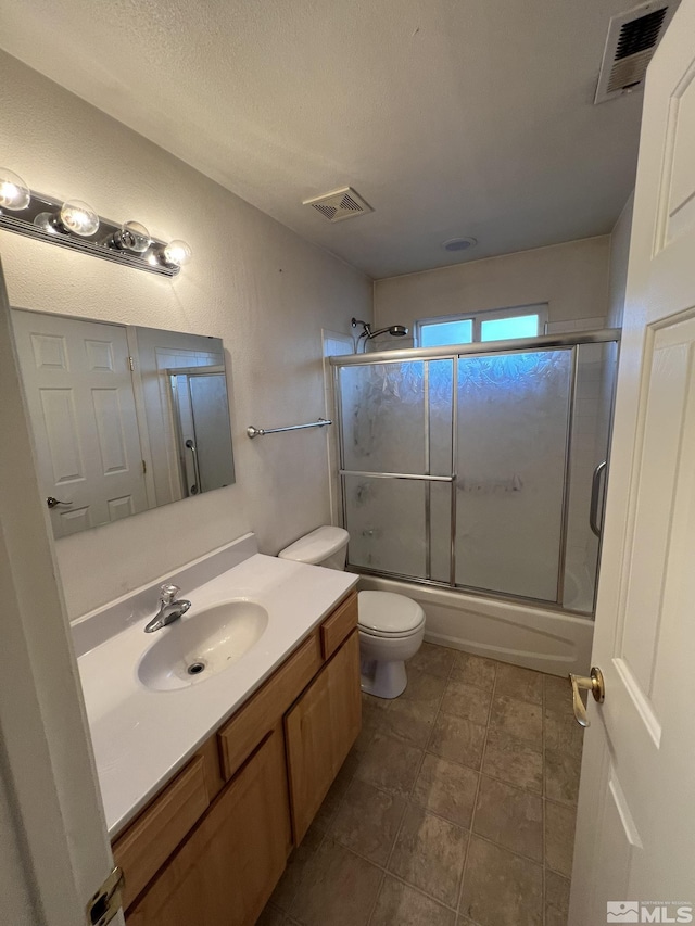 full bathroom with vanity, toilet, enclosed tub / shower combo, and a textured ceiling