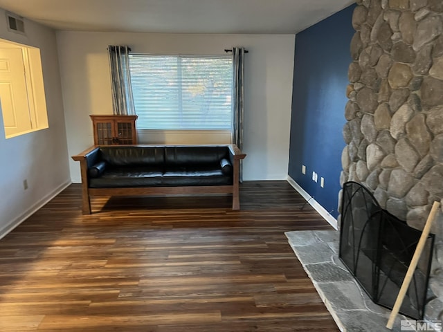 sitting room featuring a stone fireplace and dark wood-type flooring