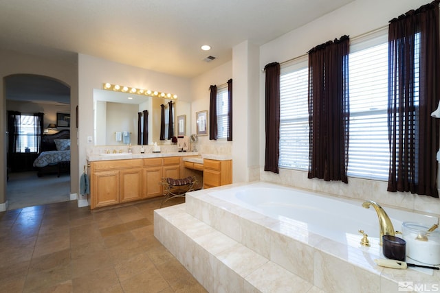 bathroom featuring tiled tub and vanity