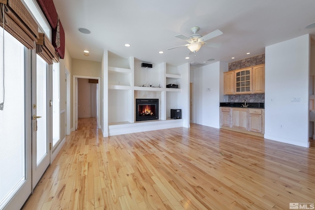 unfurnished living room with plenty of natural light, light hardwood / wood-style floors, and built in shelves