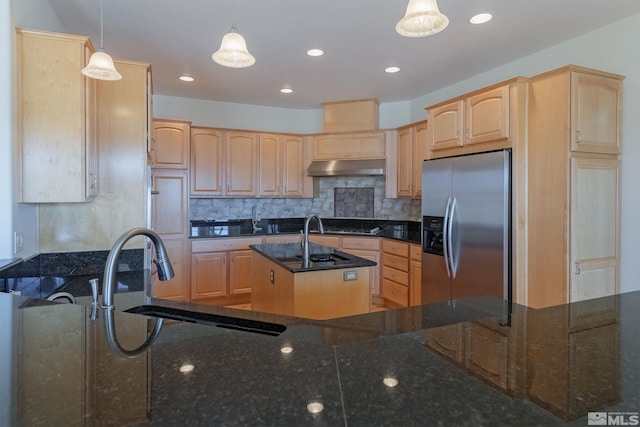 kitchen featuring appliances with stainless steel finishes, a kitchen island with sink, pendant lighting, and dark stone countertops