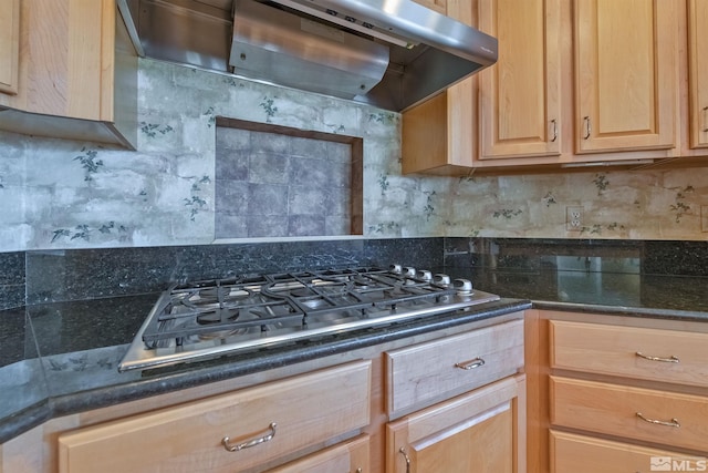 kitchen with dark stone counters, tasteful backsplash, light brown cabinetry, stainless steel gas cooktop, and extractor fan