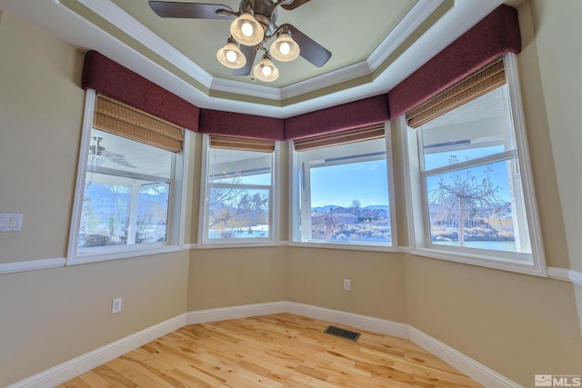 spare room with hardwood / wood-style floors, ceiling fan, crown molding, and a tray ceiling