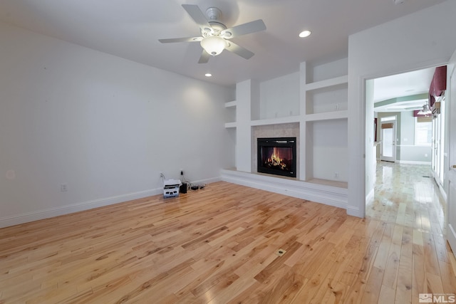 unfurnished living room with light wood-type flooring, built in features, and ceiling fan