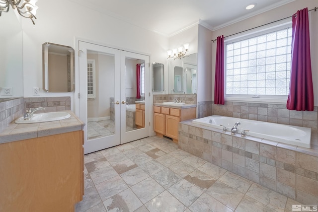 bathroom featuring french doors, vanity, crown molding, tiled tub, and a chandelier