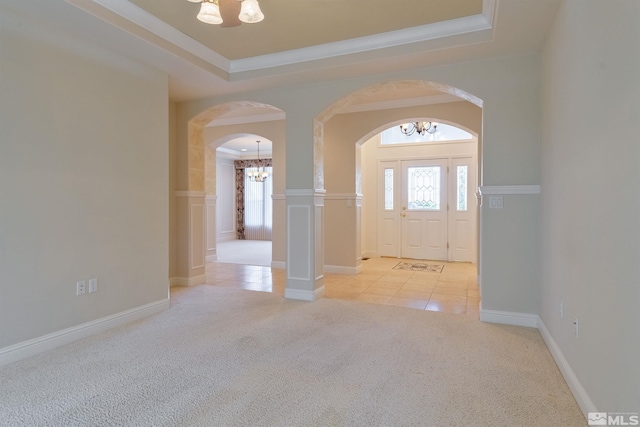 entrance foyer featuring light carpet, ornamental molding, a raised ceiling, and a notable chandelier