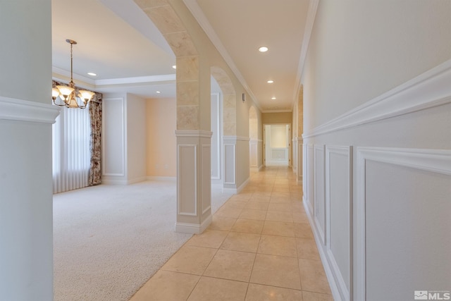 hallway with a chandelier, light colored carpet, and ornamental molding