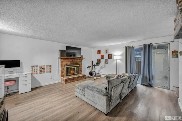 living room with a brick fireplace, a textured ceiling, and light hardwood / wood-style flooring