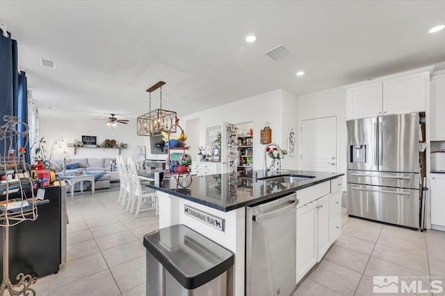 kitchen with stainless steel appliances, ceiling fan, sink, white cabinets, and an island with sink