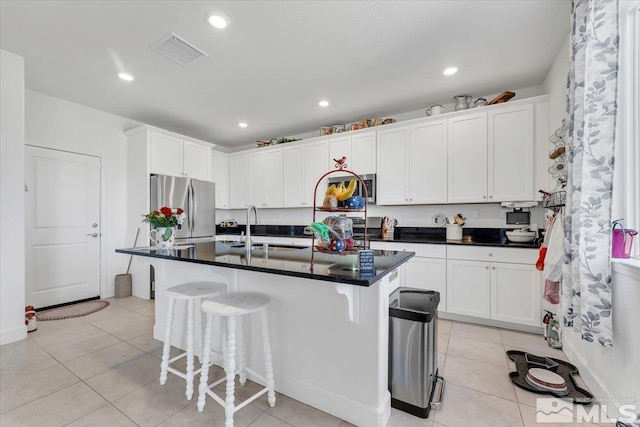 kitchen featuring white cabinetry, sink, an island with sink, a breakfast bar area, and appliances with stainless steel finishes