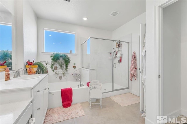 bathroom featuring plus walk in shower, vanity, and tile patterned flooring