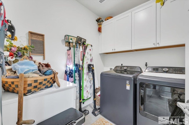 clothes washing area with cabinets and washing machine and clothes dryer