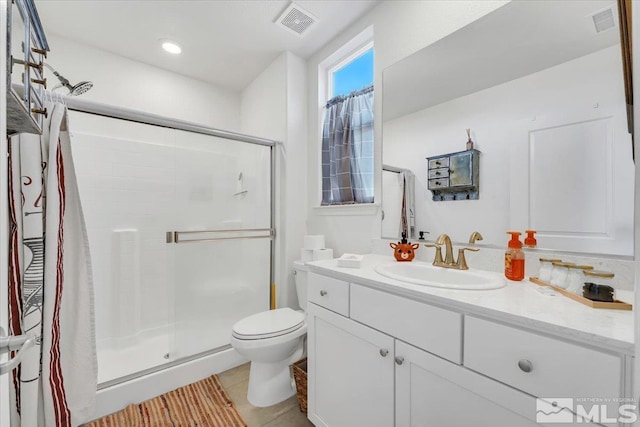 bathroom with tile patterned floors, a shower with door, vanity, and toilet