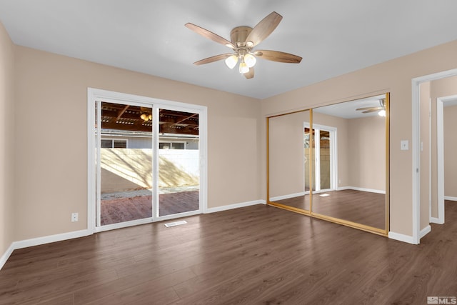 unfurnished bedroom featuring access to exterior, ceiling fan, a closet, and dark wood-type flooring