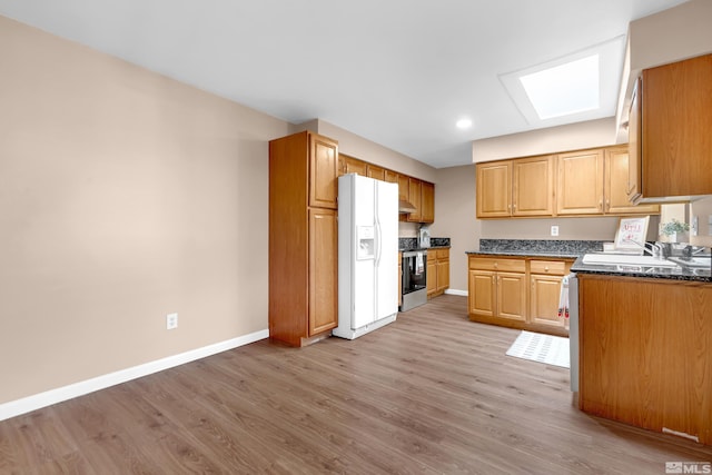 kitchen with a skylight, electric range, light hardwood / wood-style floors, and white fridge with ice dispenser