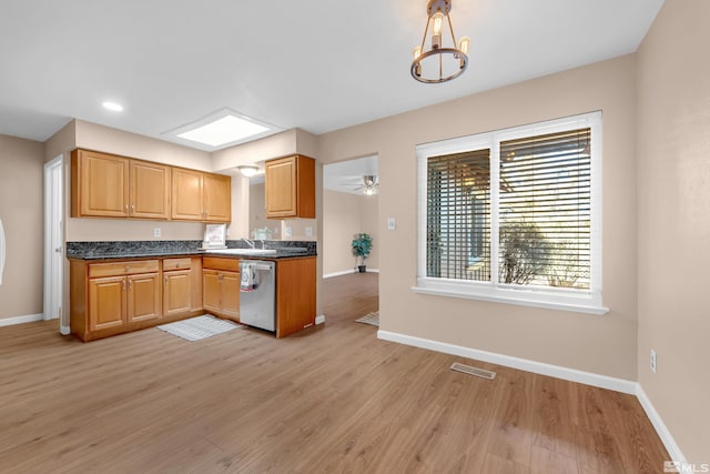 kitchen with pendant lighting, sink, a skylight, stainless steel dishwasher, and light hardwood / wood-style floors