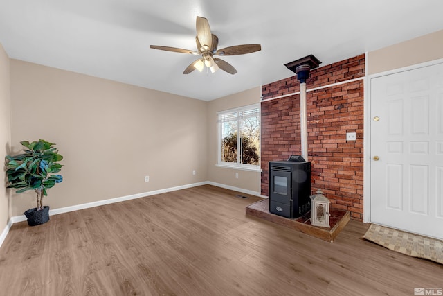 unfurnished living room with hardwood / wood-style flooring, ceiling fan, and a wood stove