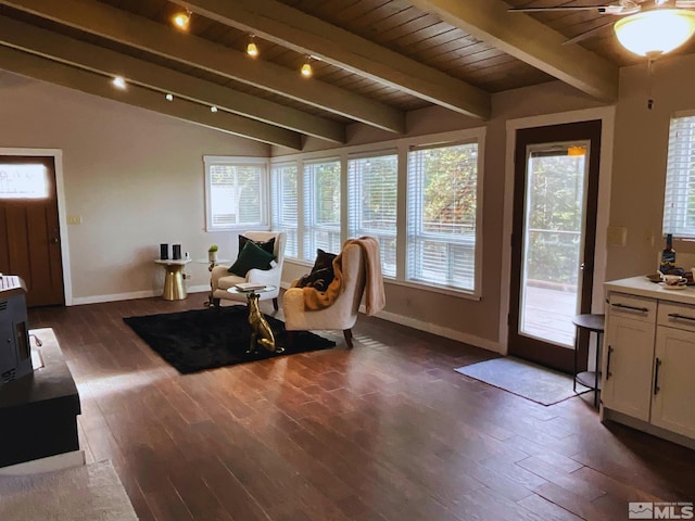 sunroom featuring vaulted ceiling with beams, a wealth of natural light, ceiling fan, and a wood stove