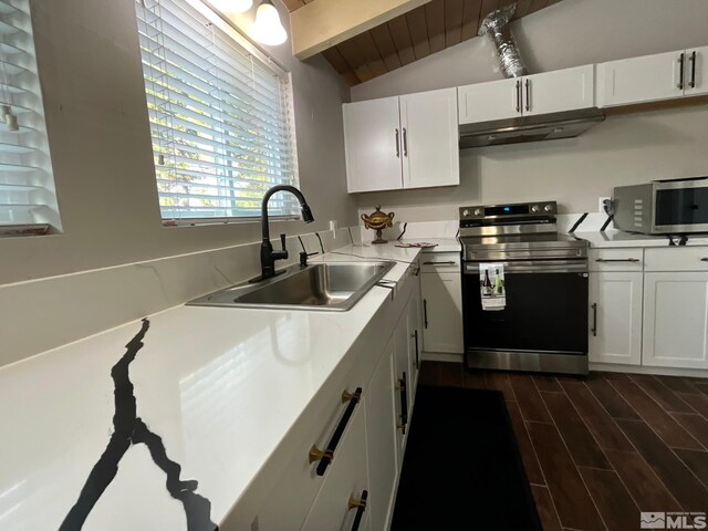 kitchen with white cabinets, appliances with stainless steel finishes, lofted ceiling with beams, and sink