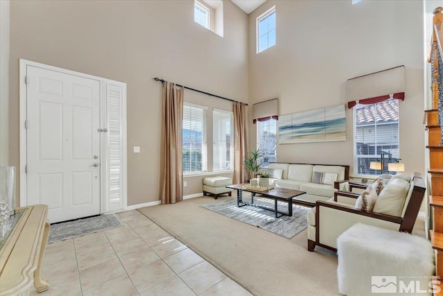 living room with a towering ceiling, plenty of natural light, and light tile patterned flooring