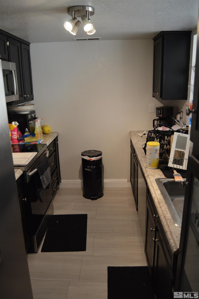 kitchen featuring electric range, light stone countertops, sink, and a textured ceiling