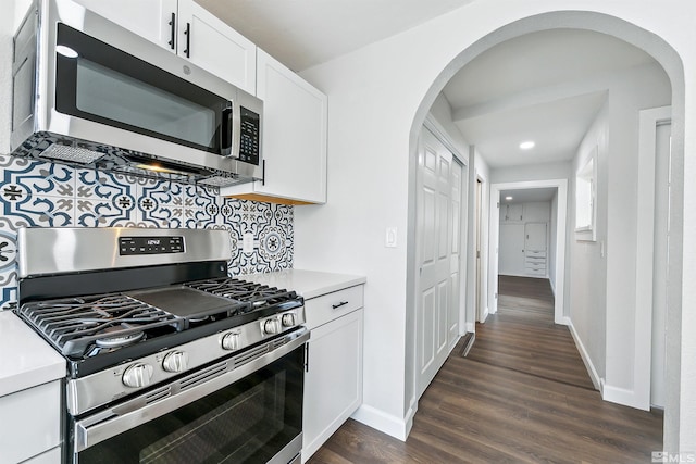 kitchen with tasteful backsplash, white cabinetry, dark wood-type flooring, and appliances with stainless steel finishes