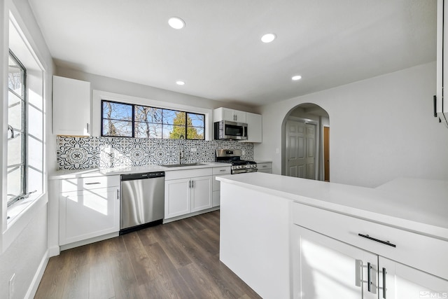 kitchen featuring sink, dark hardwood / wood-style flooring, backsplash, white cabinets, and appliances with stainless steel finishes