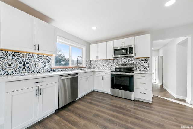 kitchen with white cabinets, dark hardwood / wood-style flooring, appliances with stainless steel finishes, and tasteful backsplash