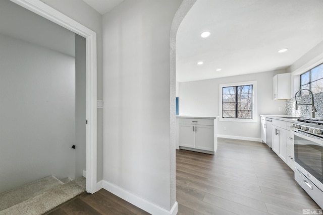 kitchen with white cabinetry, stainless steel range with gas cooktop, a healthy amount of sunlight, and sink