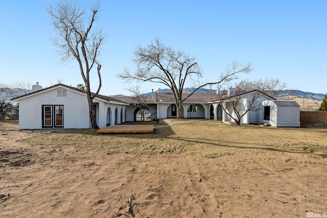 rear view of property with a deck with mountain view, a shed, and a lawn