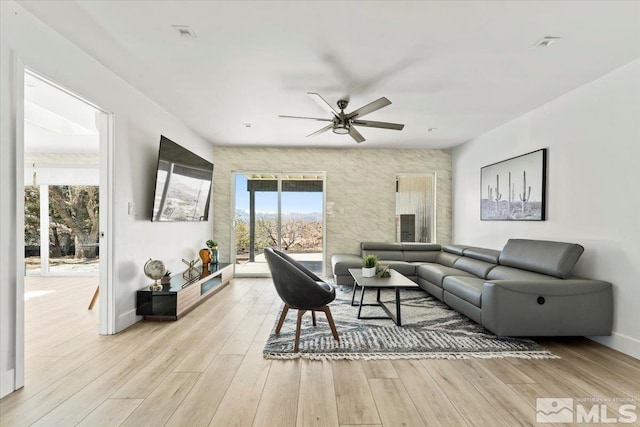 living room with ceiling fan, plenty of natural light, and light hardwood / wood-style floors