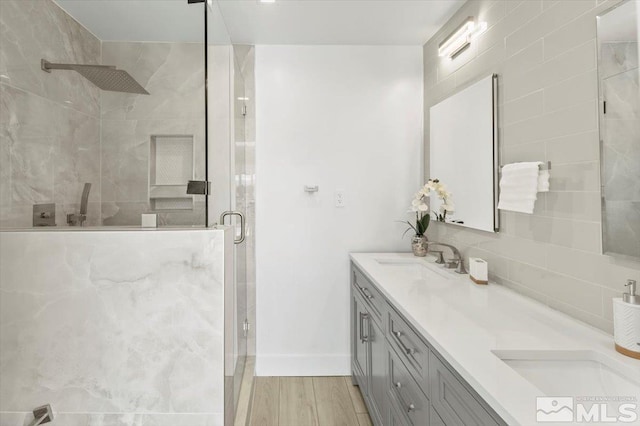 bathroom with hardwood / wood-style floors, vanity, an enclosed shower, and backsplash