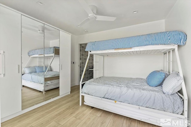 bedroom with ceiling fan, a closet, and wood-type flooring