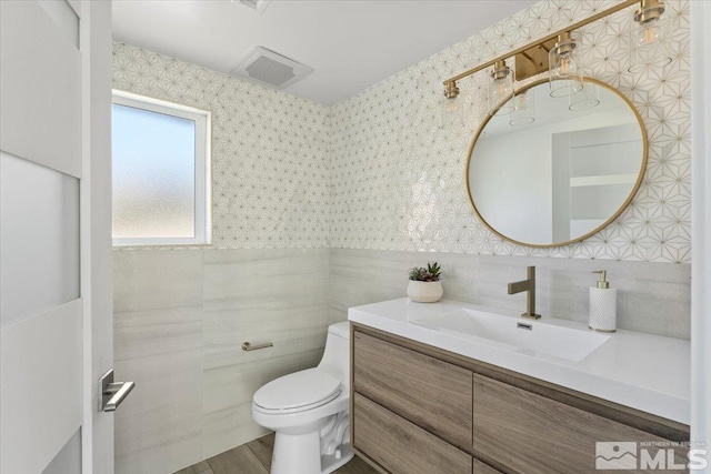 bathroom featuring hardwood / wood-style floors, vanity, tile walls, and toilet