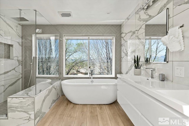 bathroom featuring hardwood / wood-style floors, vanity, tile walls, and shower with separate bathtub