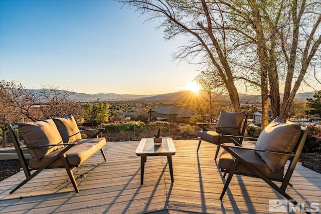 deck at dusk featuring a mountain view and an outdoor hangout area