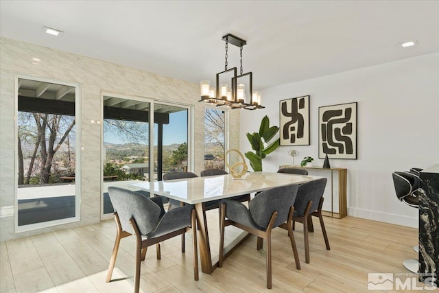 dining space featuring light hardwood / wood-style floors, tile walls, and an inviting chandelier