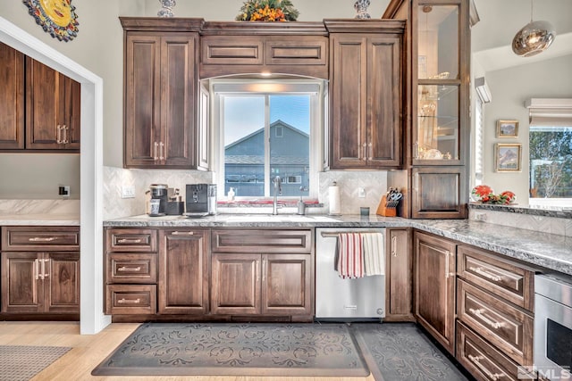 kitchen with sink, light stone counters, light hardwood / wood-style flooring, decorative backsplash, and appliances with stainless steel finishes