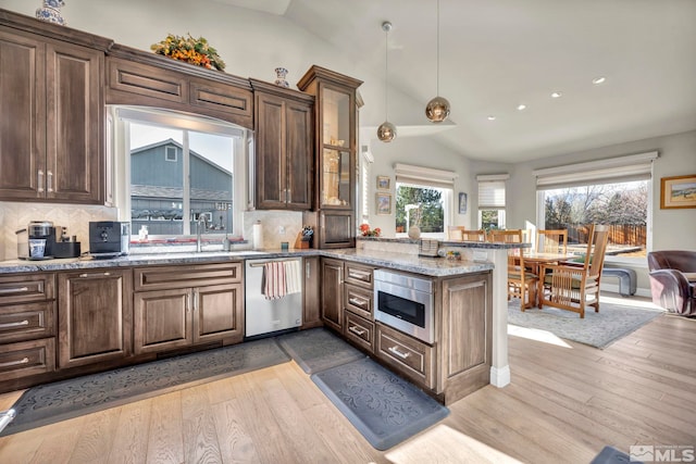 kitchen with lofted ceiling, decorative backsplash, light hardwood / wood-style floors, kitchen peninsula, and stainless steel appliances